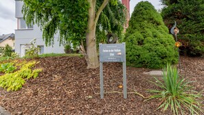 A sign with text, a tree, and a building in the background. - Apartment 'In Der Vulkan-Eifel' with Wi-Fi (Mendig)