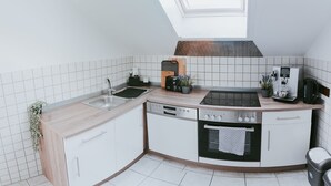A modern kitchen with a skylight, white cabinetry, a dishwasher, an oven, and a coffee machine. - Apartment 'Wadee' with Lake View, Balcony and Wi-Fi (Radolfzell am Bodensee)