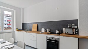 A modern kitchen with white cabinets, a wooden countertop, a built-in oven, and a window with a view of buildings. - Holiday Apartment '1st Floor Left' with Balcony and Wi-Fi (Pforzheim)