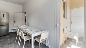 A modern kitchen with a stainless steel refrigerator, a dining table with white chairs, and a white door. - Holiday Apartment '1st Floor Left' with Balcony and Wi-Fi (Pforzheim)