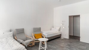 A modern room with a bed, two armchairs, a small stool, and a bedside table. - Holiday Apartment '1st Floor Left' with Balcony and Wi-Fi (Pforzheim)
