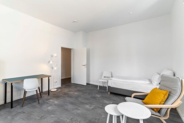 A modern room with a bed, a desk, a chair, and a small table.