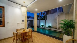 A modern interior with a dining area, a pool, and a staircase. -  Umber Rise Villa (Bali)