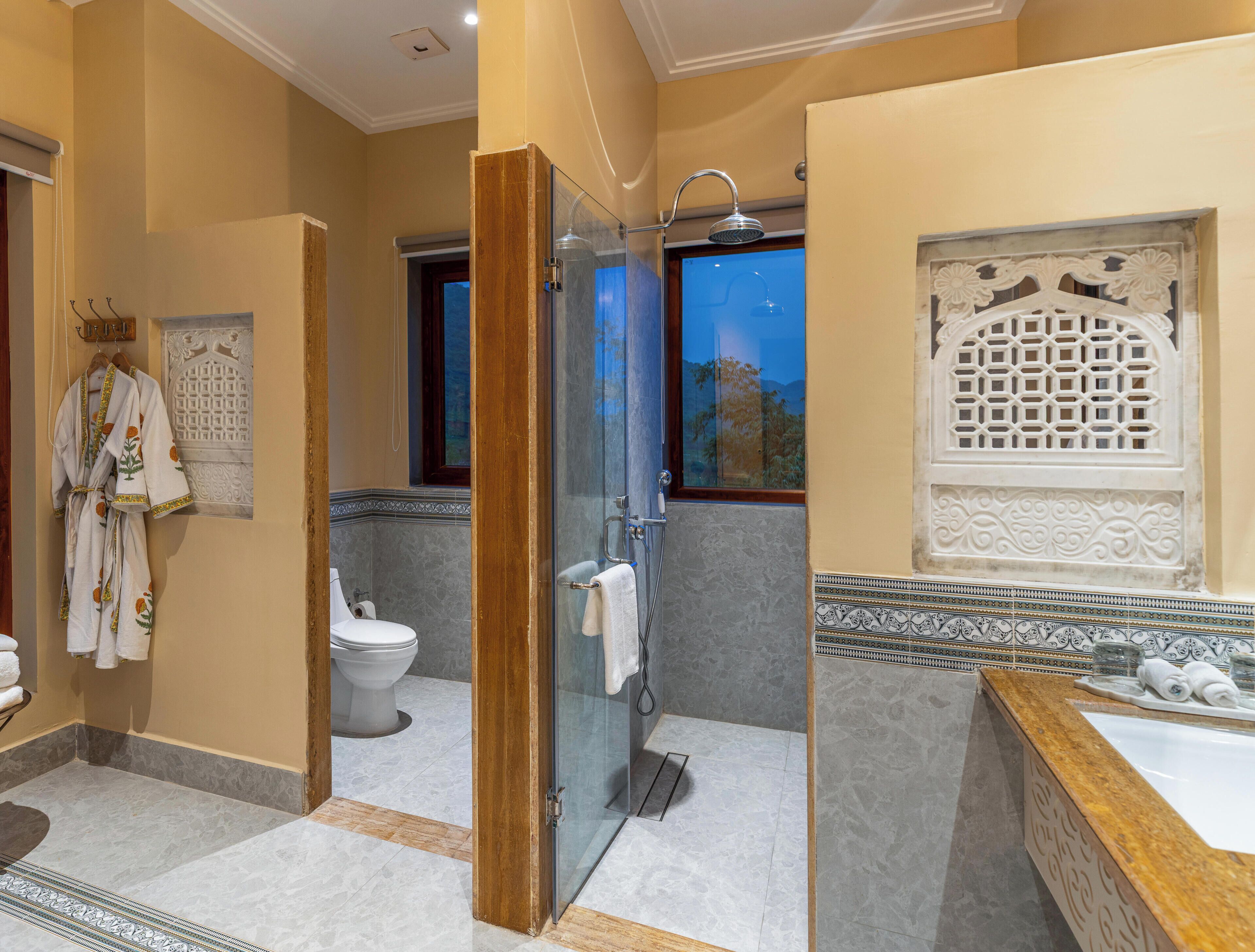 A bathroom with a glass shower enclosure, a toilet, and a sink with decorative tiles.
