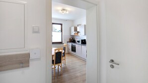 A modern kitchen with white cabinets, a microwave, and a dining area with a table and chairs.
