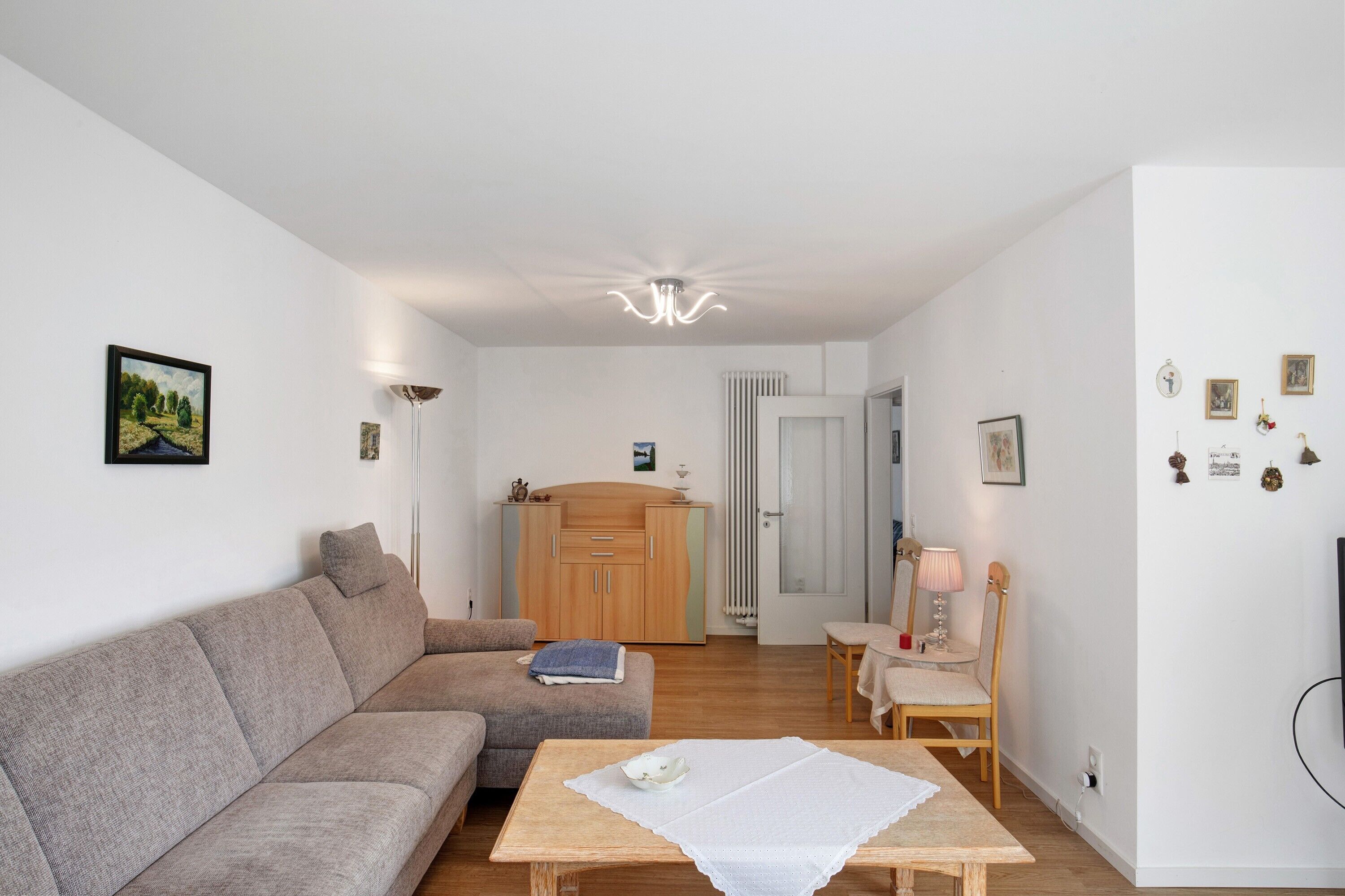 Una sala de estar con un sofá, una mesa, un aparador y una puerta que da a otra habitación.