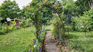A garden pathway with a vine-covered archway leading to a house.