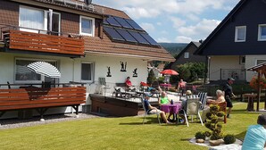 A building with a patio area, outdoor seating, and solar panels on the roof. - Apartment 9: Feel at Home Away from Home – Great Comfort with Wi-Fi & EV Charging Station (Altenau)