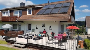 Un immeuble résidentiel doté d’un patio avec espace salon extérieur, d’un toit équipé de panneaux solaires et offrant une vue panoramique.
