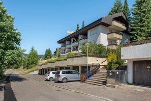 A multi-story building with a parking area, outdoor stairs, and a clear sky.