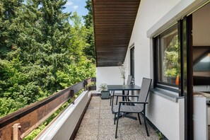 A balcony with a table and chairs, a wooden railing, and a view of dense greenery. - Apartment 'Mental Fit,  11, Todtmoos' with Mountain View, Private Terrace and Wi-Fi (Todtmoos)