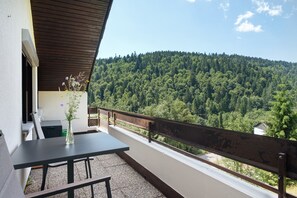 A balcony with a table and chairs, overlooking a forested hillside. - Apartment 'Mental Fit,  11, Todtmoos' with Mountain View, Private Terrace and Wi-Fi (Todtmoos)