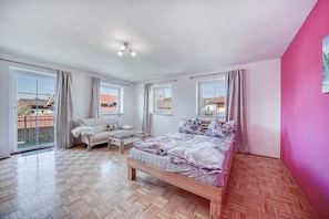 A spacious bedroom with a bed, a sofa, and a window.