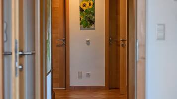 Um corredor com portas de madeira, chão de azulejos e um quadro de girassóis na parede.