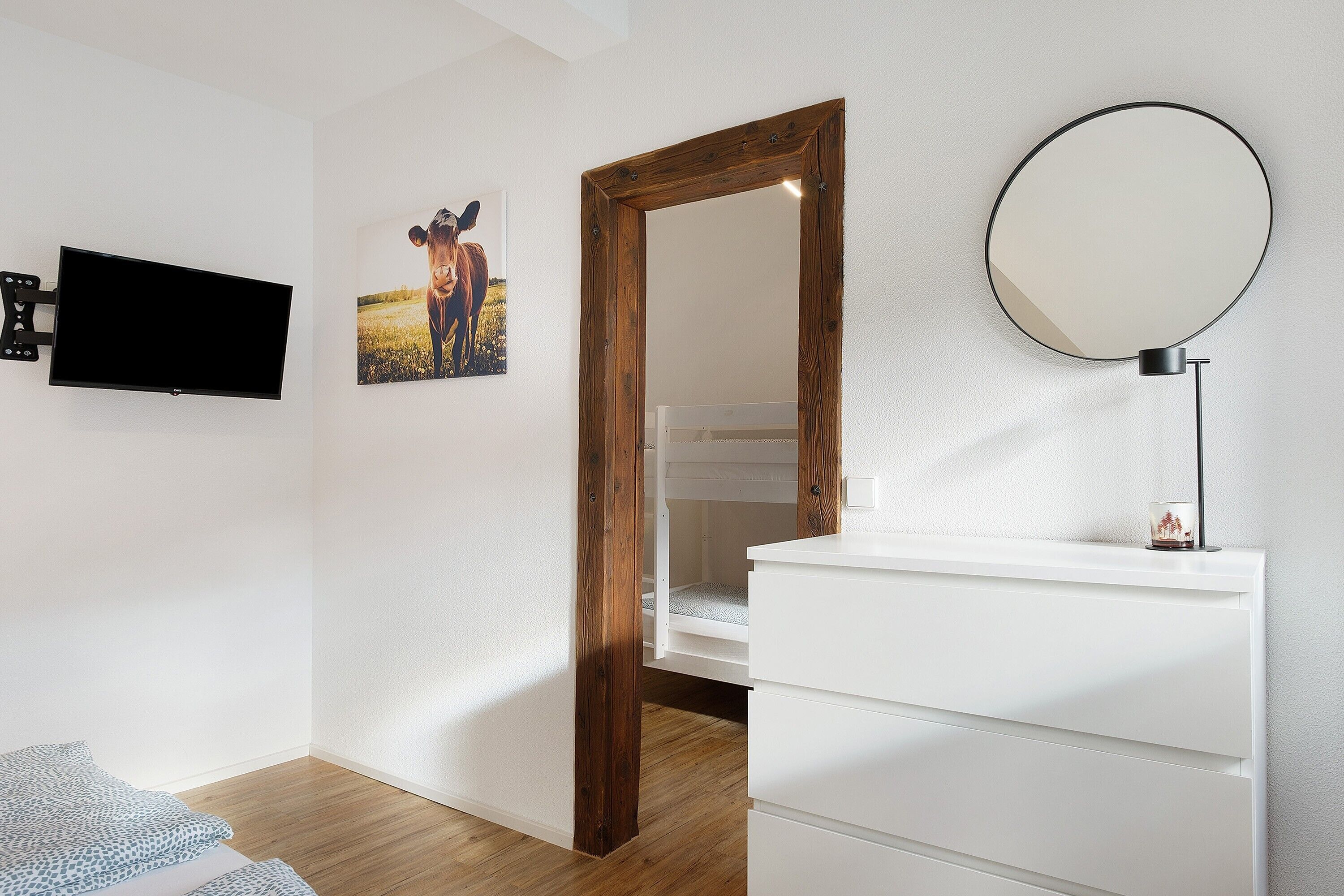A bedroom with a TV, a mirror, a bunk bed, and a bedside table.
