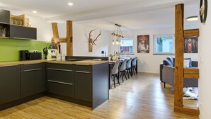 Una cocina moderna con una isla central, detalles de madera y un comedor con sillas y una mesa.