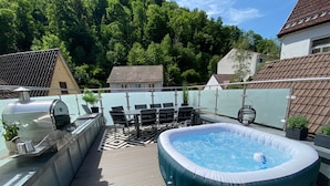 Terraza en la azotea con jacuzzi, parrilla y mobiliario exterior.