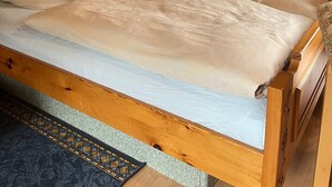 Uma cama de madeira com teto inclinado, duas almofadas e um edredom estampado.