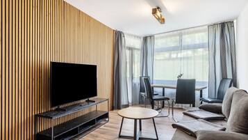 Ein modernes Wohnzimmer mit Flachbildfernseher, rundem Tisch und einer Couch.