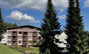 Un hotel de varios pisos con balcones, un área con césped y vista al cielo.