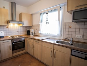 A kitchen with a stove, oven, sink, and window. - Apartment 'Adlerhorst' with Shared Garden, Balcony and Wi-Fi (Schmallenberg)