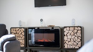 Un salon moderne avec une cheminée, un téléviseur fixé au mur et une télécommande posée sur la cheminée.