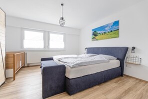 A bedroom with a bed, a window, a radiator, and a painting on the wall. - Apartment 'Adlerhorst' with Shared Garden, Balcony and Wi-Fi (Schmallenberg)