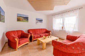 Una sala de estar con dos sofás rojos, una mesa de centro de madera y dos cuadros colgados en la pared.