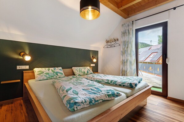 A bedroom with two beds, a wooden headboard, a ceiling light, and a view of a building through a window.