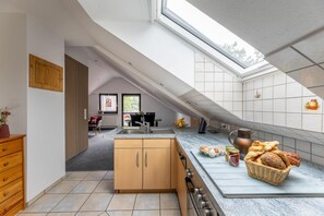 Une cuisine moderne dotée d’une verrière, de meubles en bois, d’un four encastré et d’un bar pour prendre le petit-déjeuner.