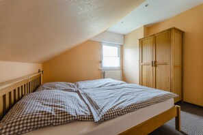 A bedroom with a bed, a window, and a wardrobe.