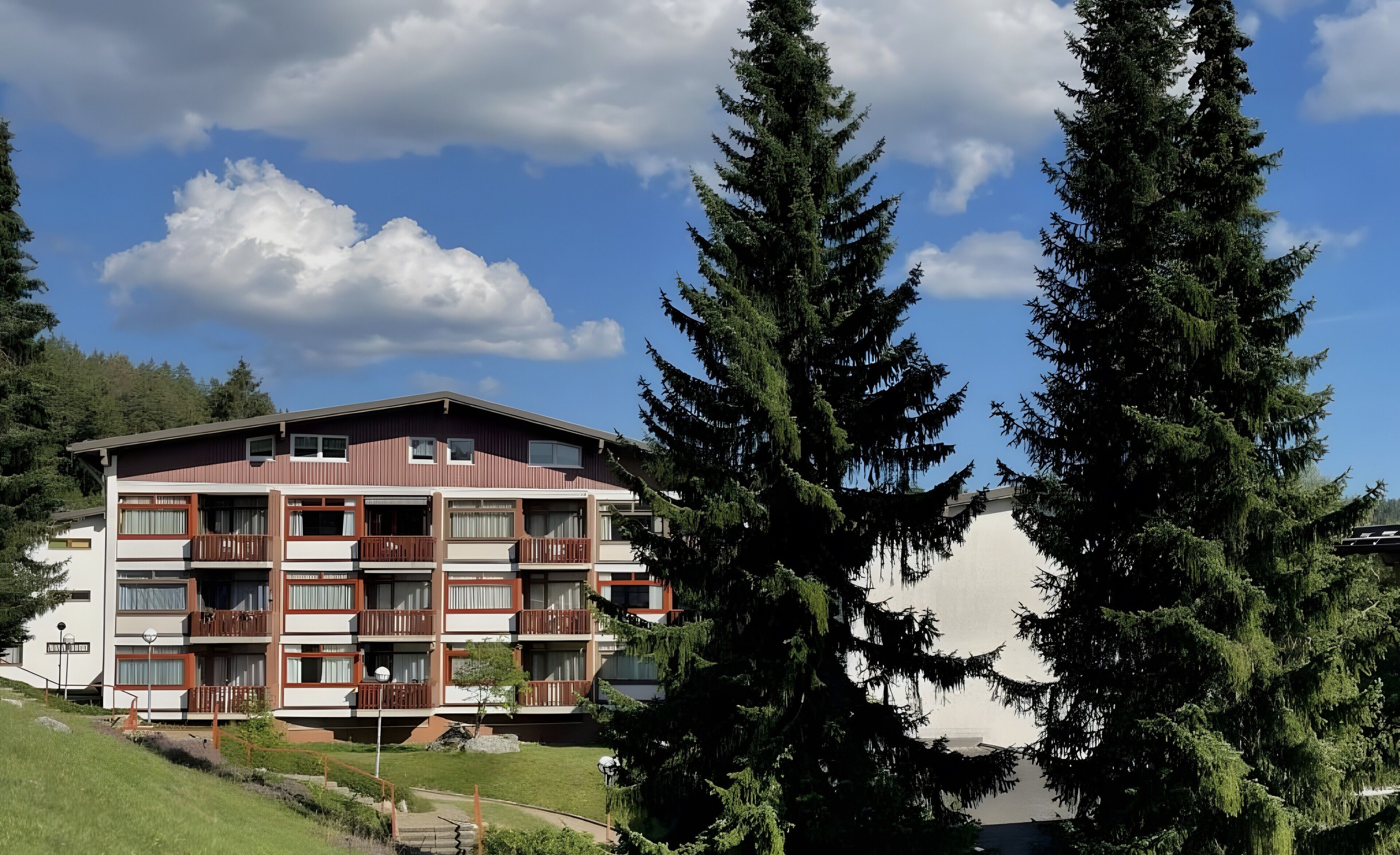 A multi-story hotel with balconies, a grassy area, and a view of the sky.
