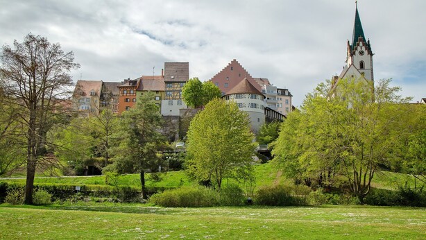 Eine historische Stadt mit einem markanten Kirchturm, üppiger Vegetation und traditioneller Architektur.