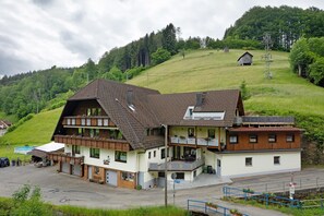 Un bâtiment à deux étages, doté d’un toit en pente, d’un balcon et d’une petite structure adjacente.