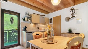 Una cucina moderna con mobili in legno, un tavolo da pranzo con sedie, una sveglia e vista sull'esterno.