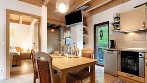 Una cucina moderna con mobili in legno, forno integrato e zona pranzo con tavolo e sedie in legno.