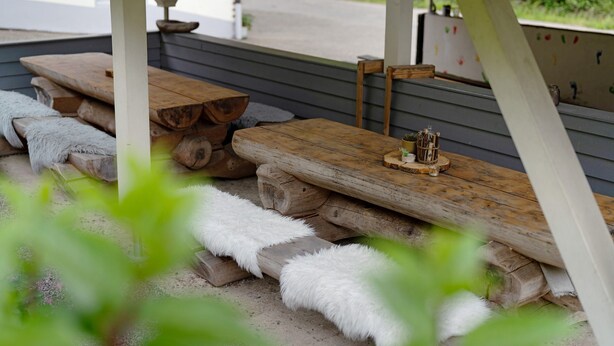 Un'area esterna coperta con panche in legno e un'atmosfera rustica.