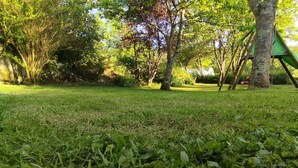 Ein Park mit Rasenfläche, Bäumen und einer grünen Rutsche.