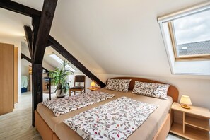 Un dormitorio con una cama grande, un escritorio, una silla, una planta en maceta y una ventana.