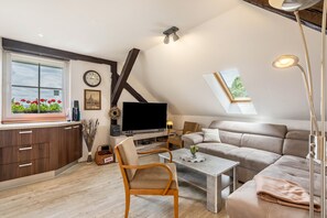 Um apartamento moderno do tipo loft, com cama em mezzanine, TV de tela plana, área de jantar e uma janela grande com vista.