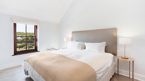 Une chambre avec un grand lit, une fenêtre donnant sur un beau paysage et une table de chevet avec une lampe.