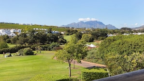 Un parcours de golf offrant une vue sur les montagnes et les maisons blanches en arrière-plan.