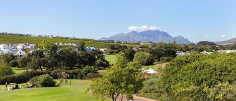 A golf course with a view of mountains and white houses in the background.