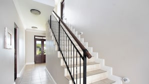Un escalier avec une rampe en bois et des balustres noires, menant à une porte dotée d’un panneau de verre.