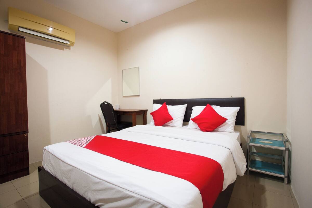A hotel room with a bed, a desk, and a wardrobe.