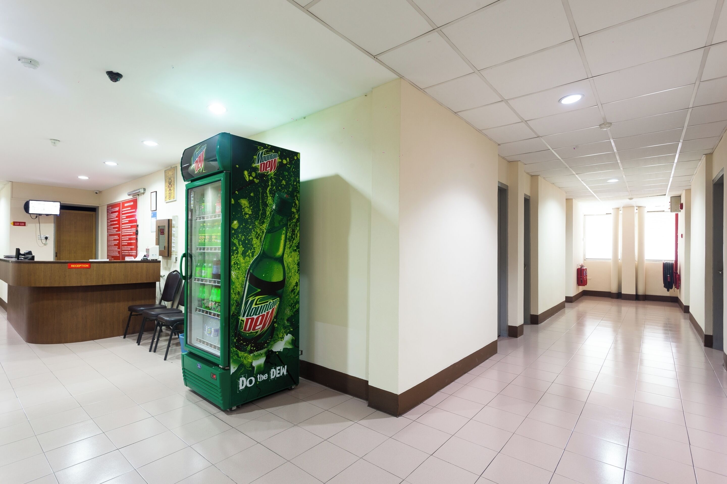 A spacious hallway with a reception desk, a vending machine, and a fire extinguisher.