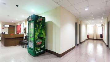 A spacious hallway with a reception desk, a vending machine, and a fire extinguisher.