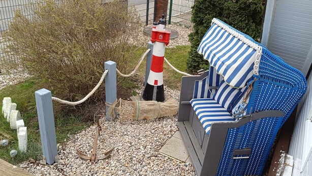 A blue and white striped outdoor seating area with a rope barrier, a lighthouse model, and a stone wall. - Holiday Home 'Ferienhaus Stamer Am Großen Meer' with Shared Terrace and Private Garden (Bedekaspel)