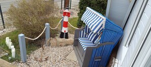 A blue and white striped outdoor seating area with a rope barrier, a lighthouse model, and a stone wall. - Holiday Home 'Ferienhaus Stamer Am Großen Meer' with Shared Terrace and Private Garden (Bedekaspel)