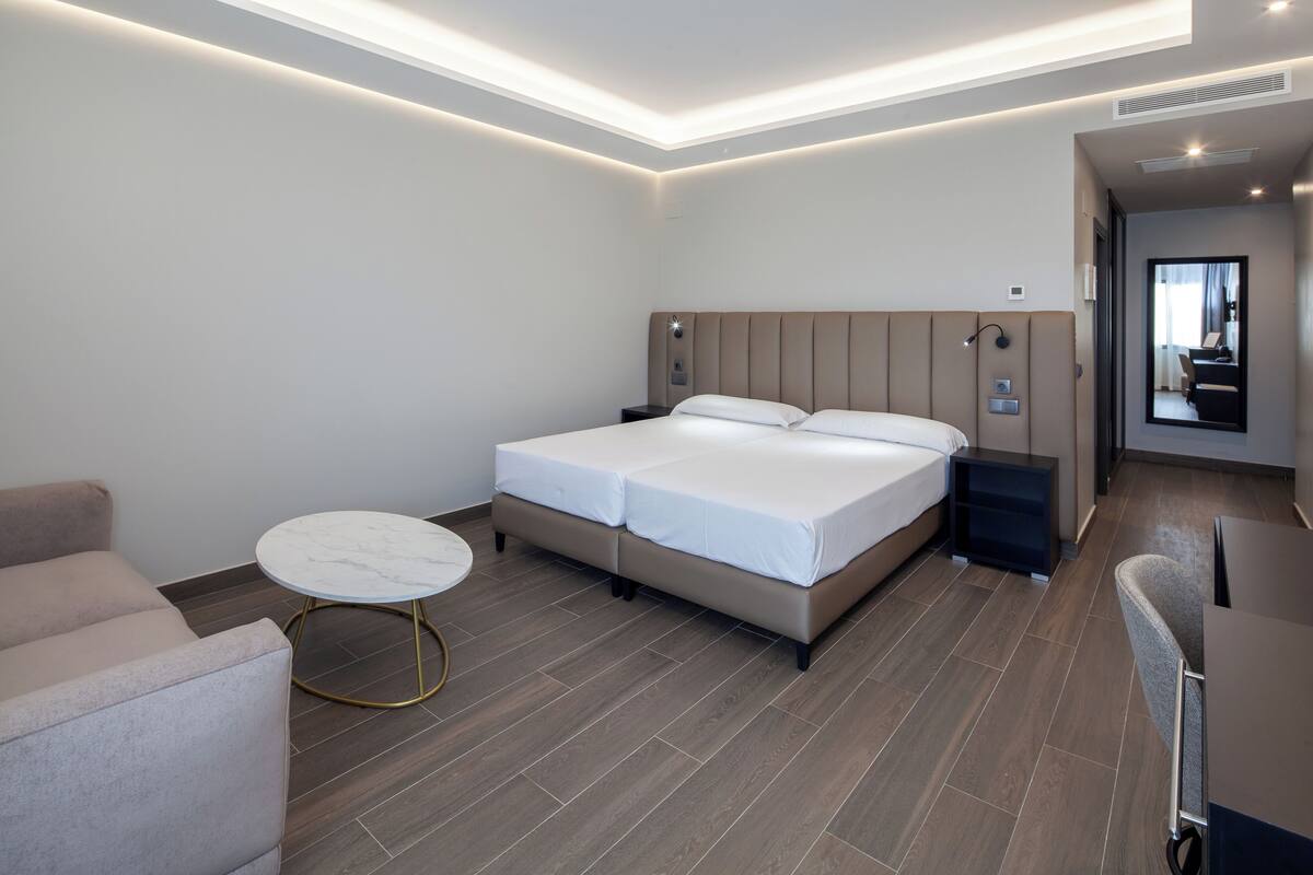 Una habitación de hotel moderna con una cama grande, una mesa redonda y un sofá.